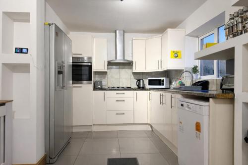 a white kitchen with white cabinets and appliances at 4-Bed Barnwell Retreat- Sleeps10 Garden & Parking in Stevenage