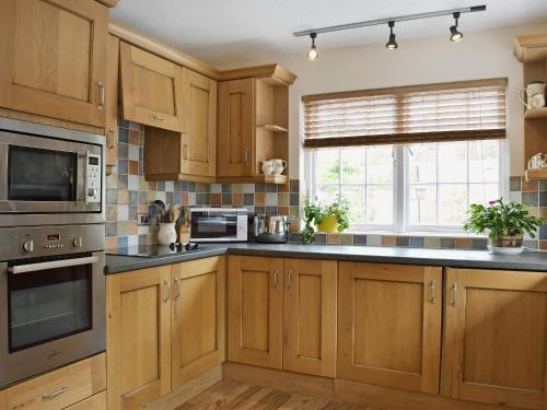 a kitchen with wooden cabinets and a large window at Ty Cornel in Aberporth