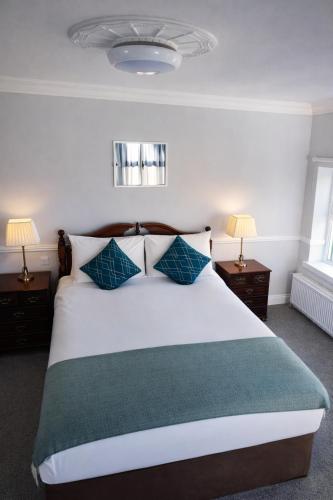 a bedroom with a large white bed with blue pillows at Aran View Holiday Homes Doolin - The Atlantic Stone House - Ocean Views in Doolin
