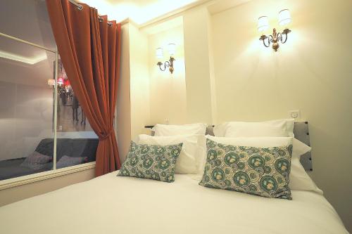 une chambre avec un lit avec des oreillers et une fenêtre dans l'établissement Louvre Opera Classic ChicSuites, à Paris