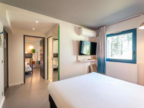 a bedroom with a white bed and a window at greet Hotel Bordeaux Aeroport in Mérignac