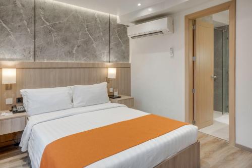 a bedroom with a large bed and a bathroom at City Garden Hotel Makati in Manila
