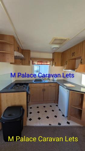 a kitchen with wooden cabinets and a black and white floor at R6 North Shore Holiday Park in Winthorpe