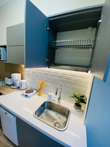 a kitchen with a sink and blue cabinets at Iconic Obelisco Studio in Buenos Aires