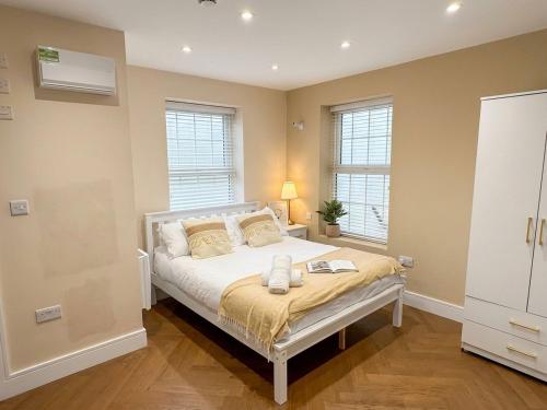 a bedroom with a bed and two windows at 30C The Luxury Studios near Arsenal and Central London in London
