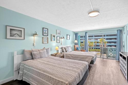 a bedroom with two beds and a balcony at Lovely Pool Front Studio in Myrtle Beach