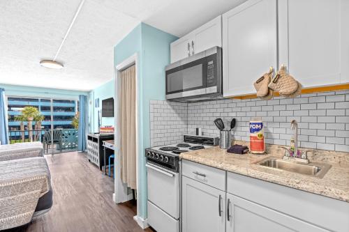 a kitchen with a sink and a stove top oven at Lovely Pool Front Studio in Myrtle Beach