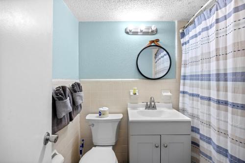 a bathroom with a toilet and a sink and a mirror at Lovely Pool Front Studio in Myrtle Beach