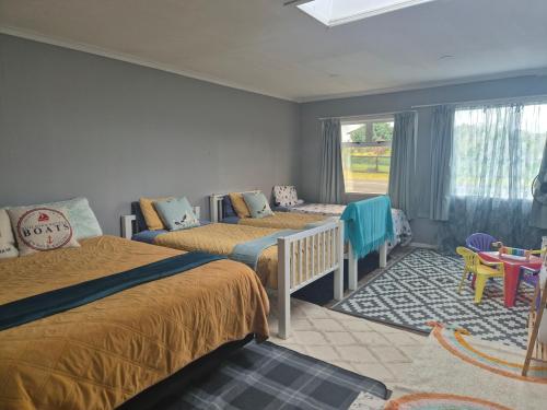 a bedroom with two beds and a table and a window at Hidden gem cheap and affordable in Te Kopuru