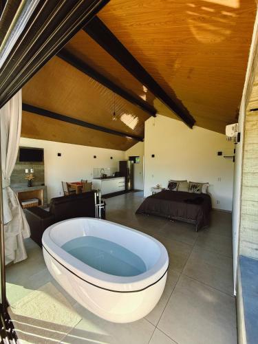 a large bath tub in a room with a bedroom at Hospedagem na natureza in Garopaba