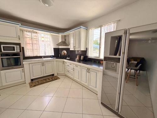 a kitchen with white cabinets and a large appliance at Sweet Nest Villa in Sainte-Rose