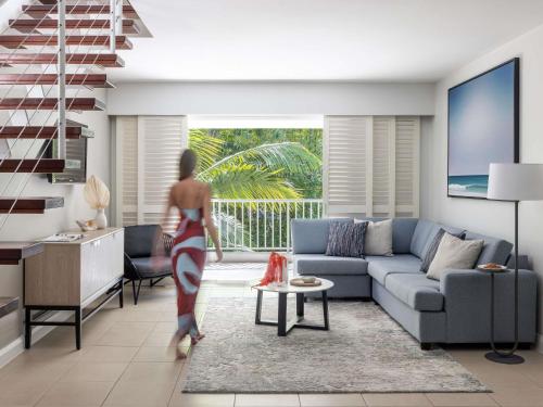 a woman walking through a living room with a couch at Peppers Beach Club & Spa in Palm Cove