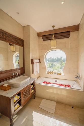 a bathroom with a tub and a sink and a mirror at Royal Roco Villa in Tanah Lot