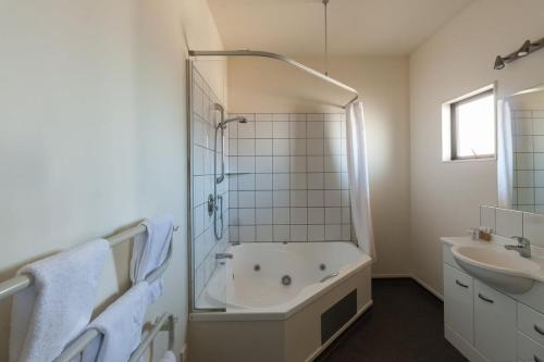 a white bathroom with a tub and a sink at Waterfront motel in Blenheim