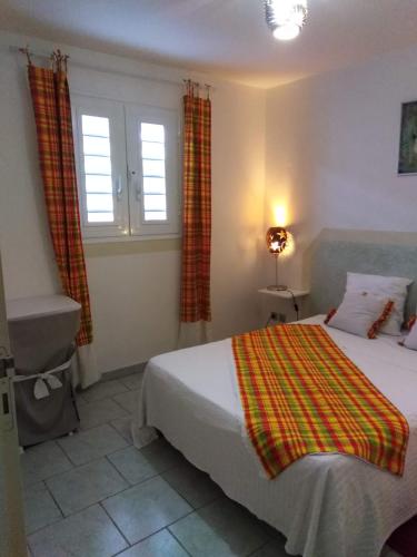 a bedroom with a bed and two windows at Villa Madras in Sainte-Anne