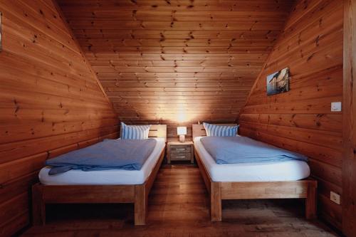 two beds in a room with wooden walls at Blockhausferien Rügen - Meerblick in Sassnitz