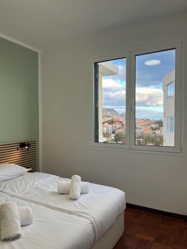 a white bedroom with two beds and two windows at Residencial do Vale in Funchal