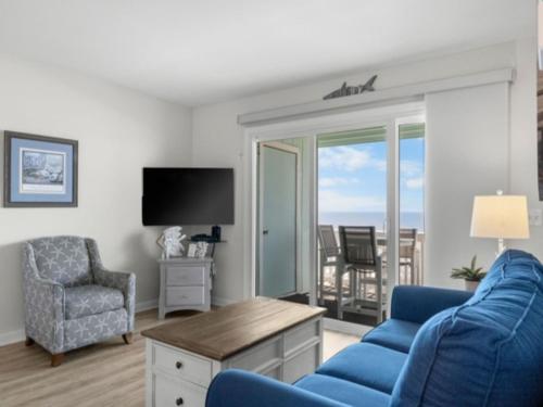 a living room with a blue couch and a chair and a television at A Beach Dream condo in Carolina Beach