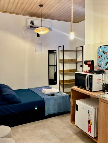 a bedroom with a bed and a microwave on a counter at Onda Studios Apê Completo - Vista Linda e Sesc Bertioga - Ar Condicionado in Bertioga