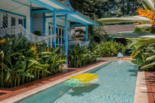 a pool in front of a blue house with a yellow pool toy at Casa Kapuas in Gili Trawangan