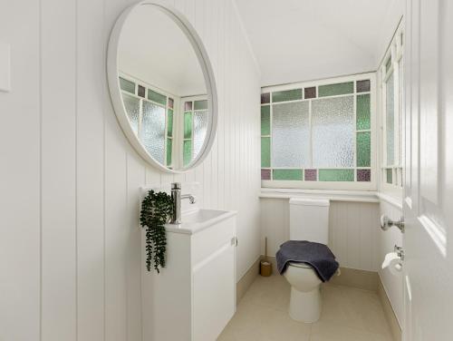 a white bathroom with a mirror and a toilet at North Ipswich 1BR Pine Studio in Ipswich