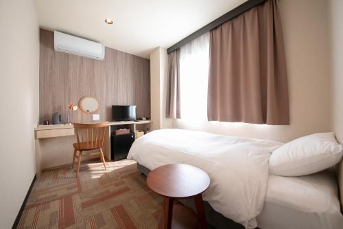 a hotel room with a bed and a table and a window at Personal Hotel You in Takeo