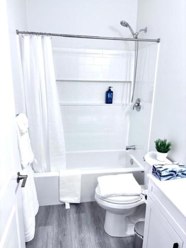 a white bathroom with a toilet and a bath tub at Cozy Home basement suite with private separate entrance in Winnipeg