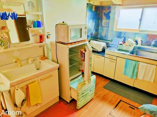 a kitchen with a refrigerator with a microwave on top at 别墅之家オーナーChangeAorB in Kami-furano