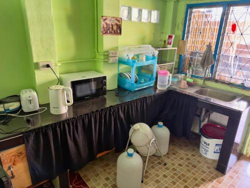a kitchen with a counter with a microwave and a sink at Penny Hostel & Cafe in Thong Sala