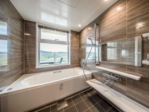 a bathroom with a tub and a window at Lieta Nakayama in Nago