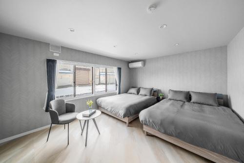 a bedroom with two beds and a chair at Villas Park Kamifurano in Kami-furano