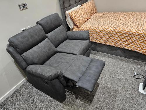 a black couch sitting next to a bed at Double En Suite Room Newcastle Upon Tyne in Derwent Haugh