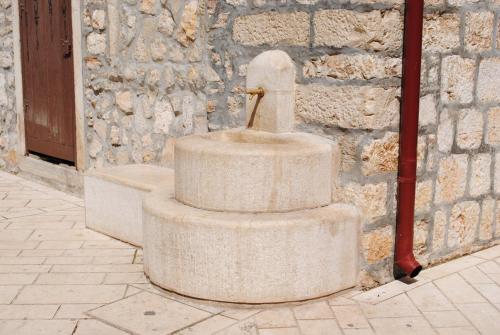 a stone fountain on the side of a building at Rooms Piazzetta in Cres