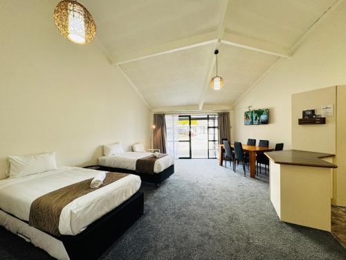 a hotel room with two beds and a table at Chelmswood Motel Taupo in Taupo