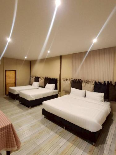 two beds in a hotel room with lights on the ceilings at กมุทมาศ สวรรคโลก in Ban Pa Muang (1)
