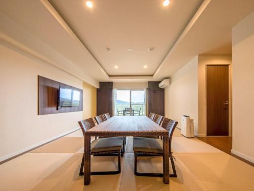 a dining room with a wooden table and chairs at Lieta Nakayama in Nago