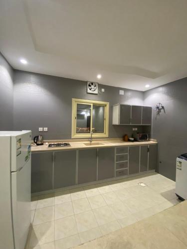 a kitchen with gray cabinets and a white refrigerator at مساكن اركان in Quai