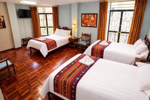a hotel room with three beds and a table at Viena Internacional B&B - Rooftop in Quito