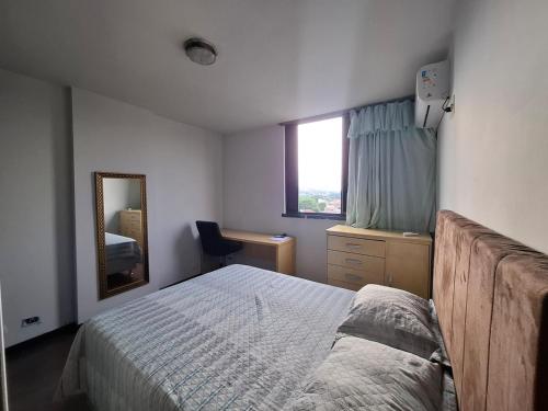 a bedroom with a bed and a mirror and a window at Apartmento Moto GP in Goiânia