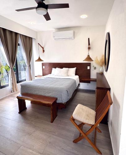 a bedroom with a bed and a bench and a fan at Villa Tucanes in Tulum