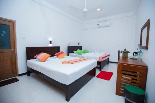 a bedroom with two beds and a dresser in it at River Shade Inn in Tissamaharama