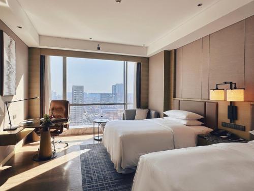a hotel room with two beds and a large window at Baotou Marriott Hotel in Baotou