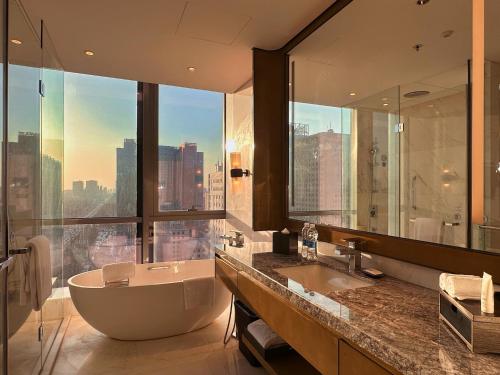 a bathroom with a tub and a large window at Baotou Marriott Hotel in Baotou