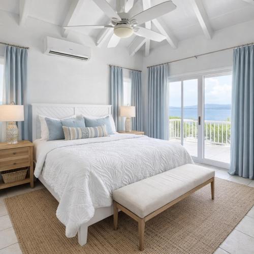 a white bedroom with a bed and a ceiling fan at The View at Green Cay - Full AC - Walk to the Beach in Christiansted