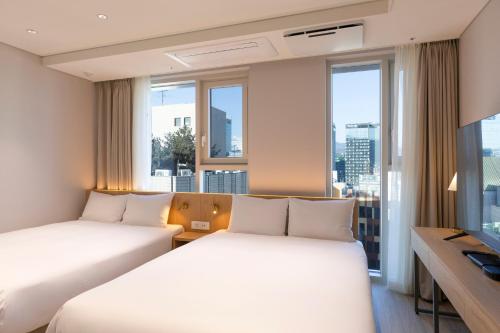 two beds in a hotel room with windows at SL Hotel Myeongdong in Seoul