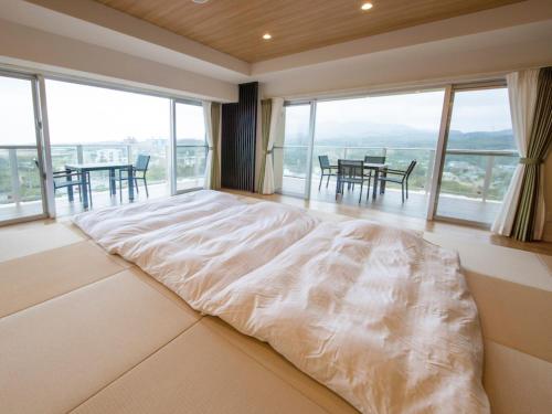 a large bed in a room with large windows at Lieta Nakayama in Nago
