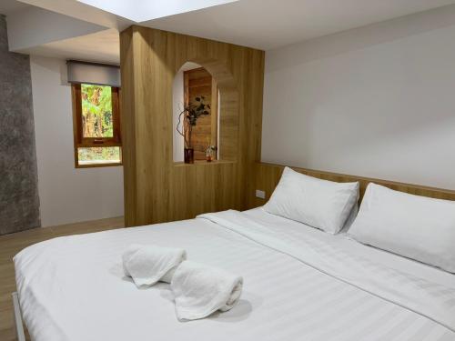 a bedroom with a white bed with towels on it at Baan Trok Bedroom Studio Maikhao in Mai Khao Beach