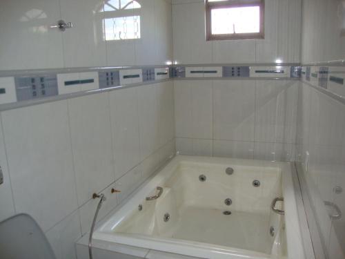 a white bath tub in a white tiled bathroom at Pousada Jesus De Nazare in Trindade