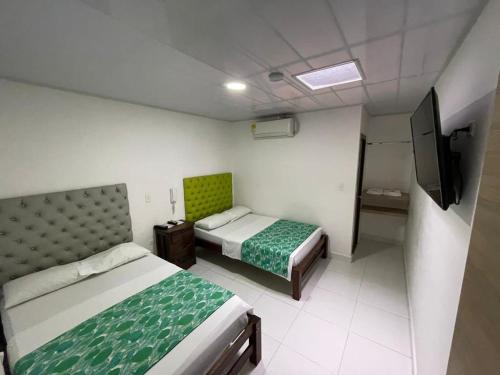 a hotel room with two beds and a flat screen tv at Hotel Limaco in Neiva