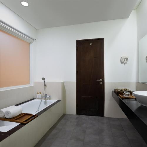 a bathroom with a sink and a tub and a toilet at Grande Padjadjaran Hotel in Kamparganya